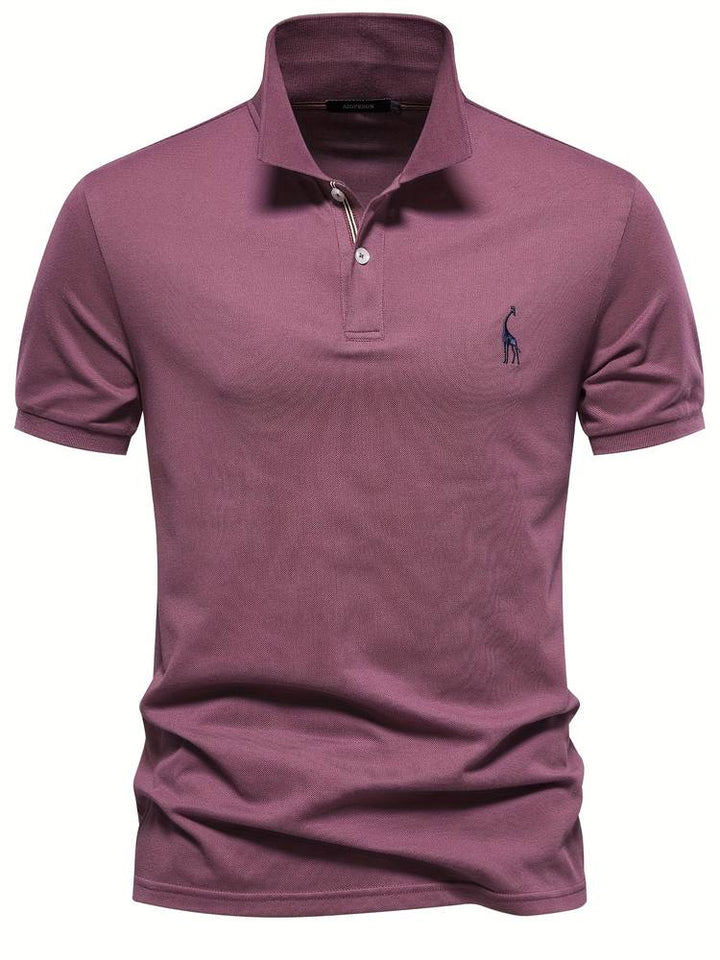 Un polo mauve élégant avec un logo de girafe brodé sur la poitrine. Ce modèle moderne et raffiné dispose d’un col classique avec des rayures discrètes à l’intérieur et des boutons contrastés, parfait pour un look décontracté et stylé.