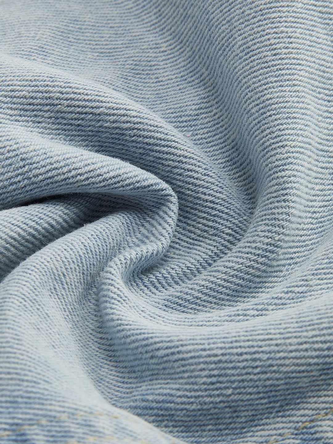 Zoom sur le tissu en denim bleu clair de la veste en jean courte Clementine. Ce denim de haute qualité présente une texture douce et légèrement texturée, parfaite pour une coupe moderne et confortable. Le tissu, à la fois léger et résistant, est idéal pour un look casual élégant et décontracté.