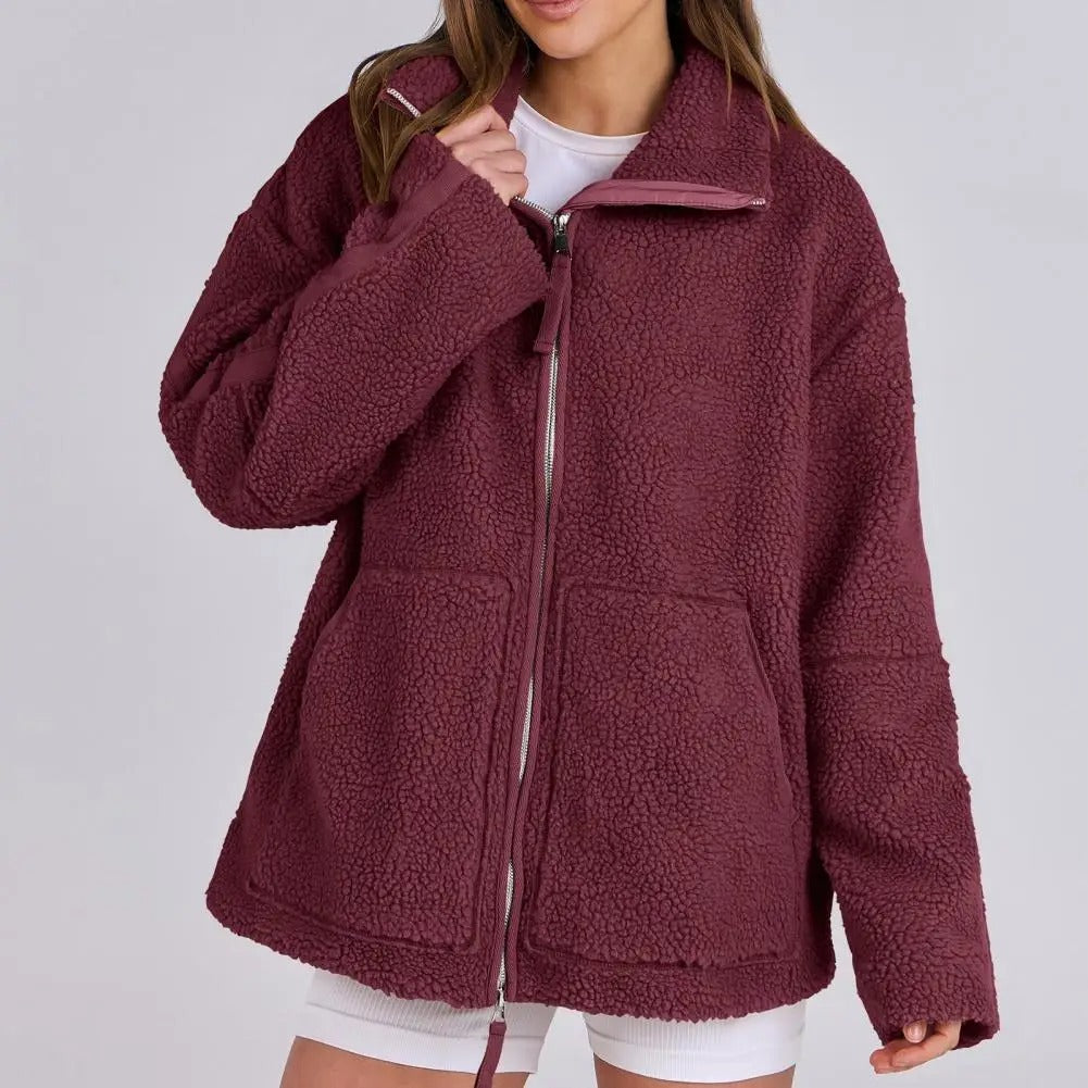 Veste rouge en peluche pour femme, douce et moelleuse. Ce modèle est doté d'une fermeture éclair sur le devant, d'un col montant et de deux grandes poches plaquées. Un style à la fois décontracté et moderne, idéal pour les journées fraîches ou pour composer des tenues d'automne et d'hiver à la fois confortables et élégantes.