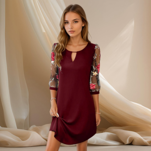 Robe bordeaux élégante à coupe fluide, avec manches 3/4 en tulle transparent imprimé floral, portée par un mannequin sur fond beige lumineux.