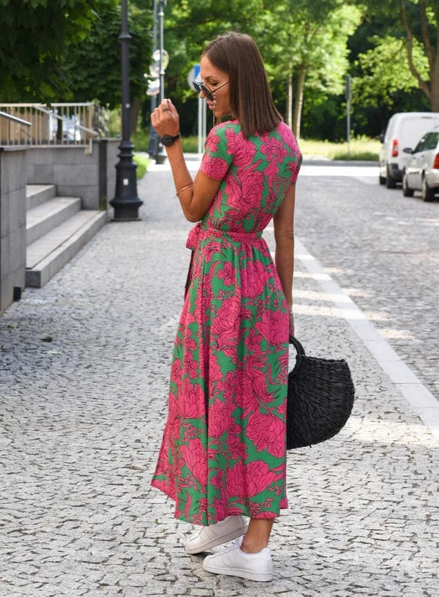 Vue arrière de la robe midi femme Demi, au style moderne avec col en V et imprimé floral rose et vert. Coupe fluide avec taille cintrée et lien à nouer, offrant une silhouette élégante et féminine, idéale pour un look estival raffiné.