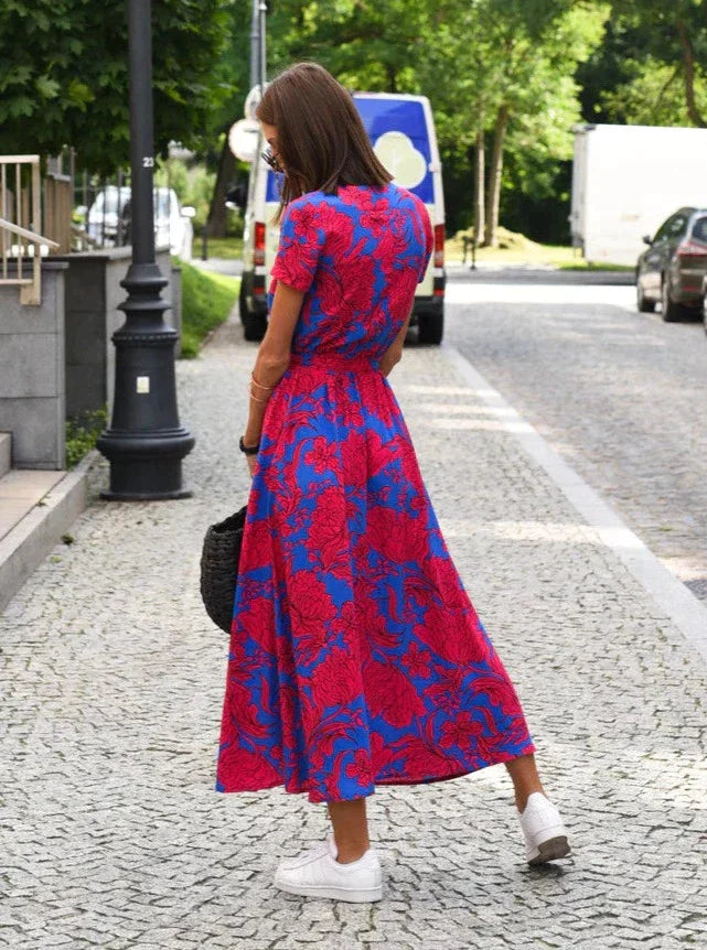 Vue arrière de la robe midi femme Demi au style moderne, avec col en V et imprimé floral rouge sur fond bleu. Coupe fluide avec taille cintrée, idéale pour une silhouette élégante et un look estival chic et tendance.