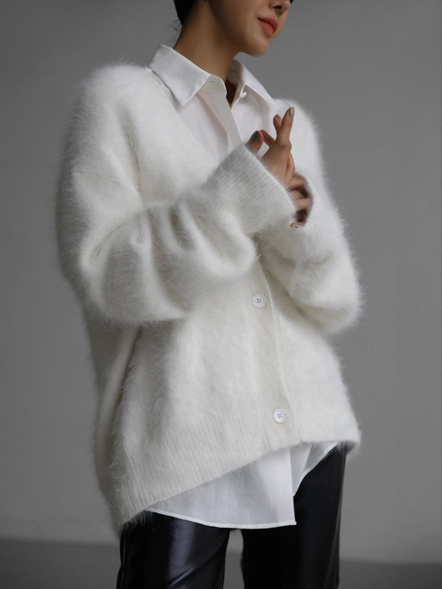 Un cardigan doux et confortable de couleur blanche, avec une coupe moderne et décontractée, agrémenté de boutons au centre et porté sur une chemise blanche. Il apporte une touche élégante et chaleureuse à la tenue.