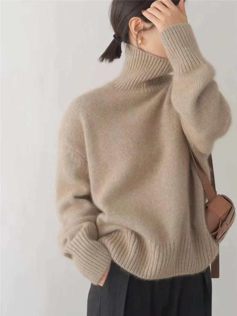 Pull à col roulé femme Éléonore beige taupe en maille douce et chaude, coupe oversize avec manches longues et finitions côtelées, porté avec un pantalon noir et un sac bandoulière — parfait pour l’hiver.