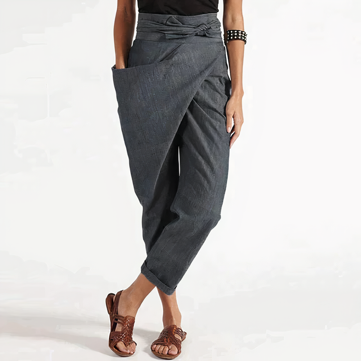 Pantalon fluide gris anthracite style portefeuille avec taille nouée, coupe ample et chevilles retroussées, porté avec sandales marron.