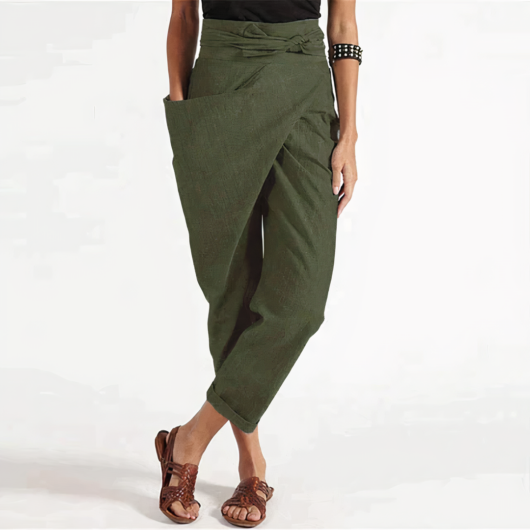 Pantalon d’été vert kaki coupe ample style portefeuille, taille haute nouée avec grand rabat et poches, chevilles retroussées, porté avec sandales marron.