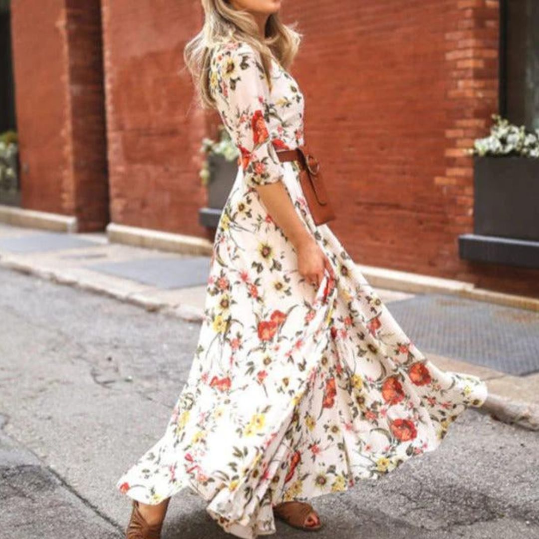 robe blanche fluide à imprimé floral coloré, manches 3/4, coupe cintrée à la taille et jupe longue évasée, portée en extérieur.