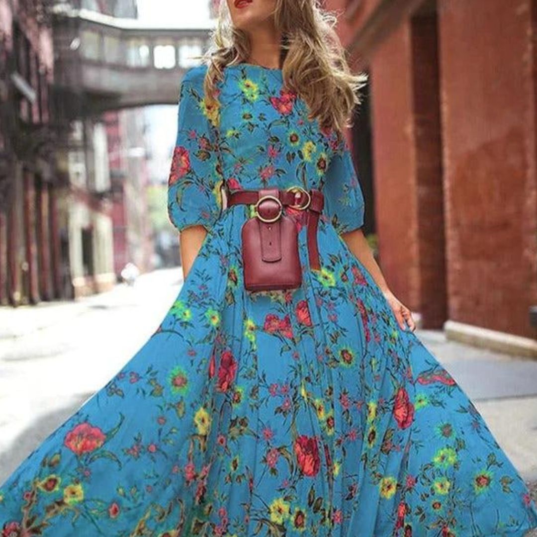 robe bleue fluide à imprimé floral multicolore, manches 3/4, taille ceinturée avec sac ceinture, jupe longue évasée en mouvement en ville.