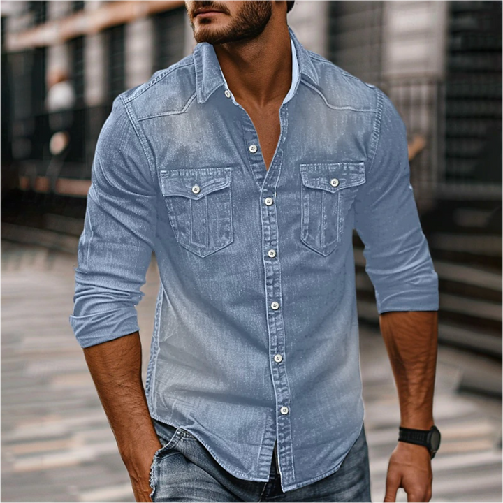 Homme portant la chemise moderne Étienne à manches longues en denim bleu clair, coupe ajustée, boutonnage et deux poches poitrine, style casual urbain.
