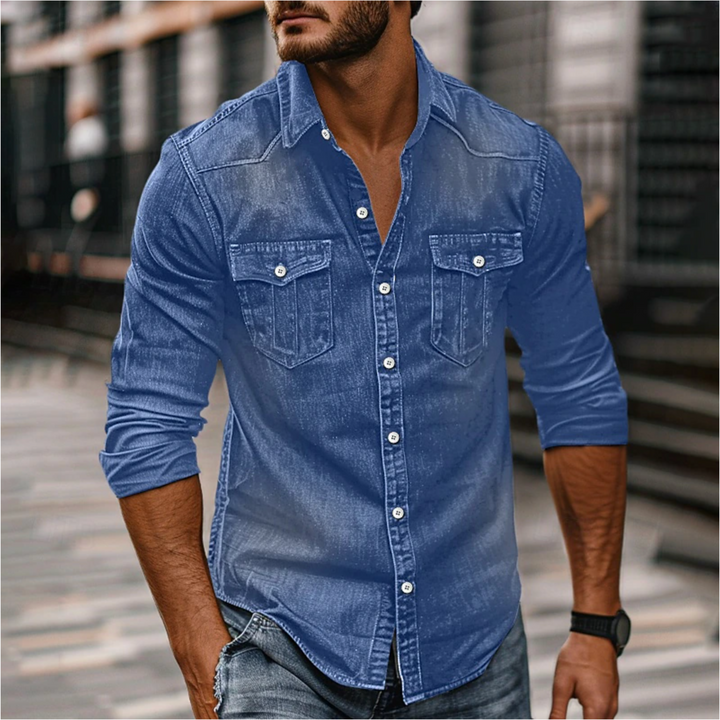 Homme portant la chemise moderne Étienne à manches longues en denim bleu, coupe ajustée, boutonnage et deux poches poitrine, style urbain décontracté.