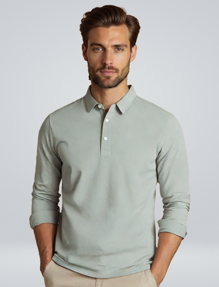 Polo à manches longues pour homme Eugène, coupe ajustée et style tendance, en tissu doux vert gris avec col classique et boutons, porté par un modèle pour un look moderne et élégant.