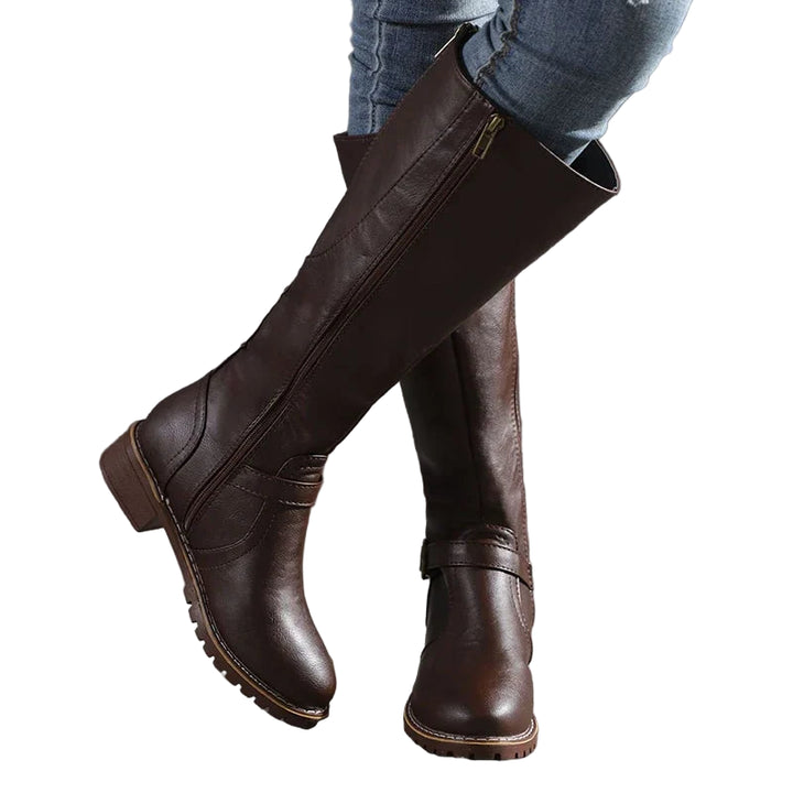 Bottes hautes marron foncé en cuir synthétique pour femme, avec fermeture éclair latérale et boucle décorative au niveau de la cheville. Design élégant et pratique, idéal pour la saison hivernale. Offrant un bon maintien et un style raffiné, elles se marient parfaitement avec un jean ou une tenue décontractée.