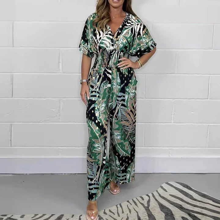 Combinaison imprimée à taille haute et jambes larges pour femme, modèle moderne. Cette combinaison présente un motif tropical avec des tons de vert, noir et doré, pour un look à la fois élégant et exotique. Elle est dotée d'une taille élastiquée qui marque la silhouette et de jambes larges, offrant confort et style pour toutes les occasions.