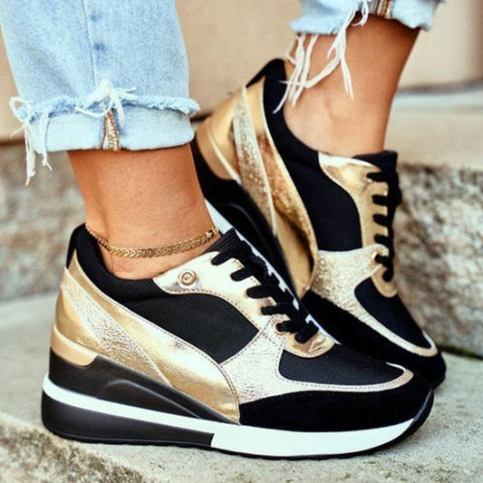 Plan rapproché de baskets noires et dorées élégantes avec une semelle à talon ergonomique et épurée, offrant à la fois élégance et confort. Portées avec un jean retroussé et effiloché et un bracelet de cheville chic, ces chaussures sont parfaites pour un look quotidien à la fois tendance et confortable.