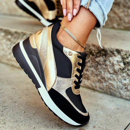 Plan rapproché de baskets noires et dorées élégantes avec une semelle à talon ergonomique, offrant confort et élégance. Portées avec un jean effiloché et un bracelet de cheville, ces chaussures allient design chic et fonctionnalité pour un look tendance au quotidien.