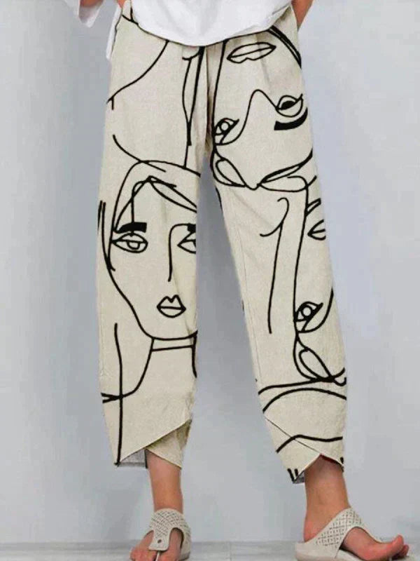 Pantalon ample d’été pour femme en tissu léger de couleur beige, avec imprimé artistique de visages en lignes noires, coupe droite fluide longueur cheville et taille confortable, porté avec des sandales sur fond neutre.