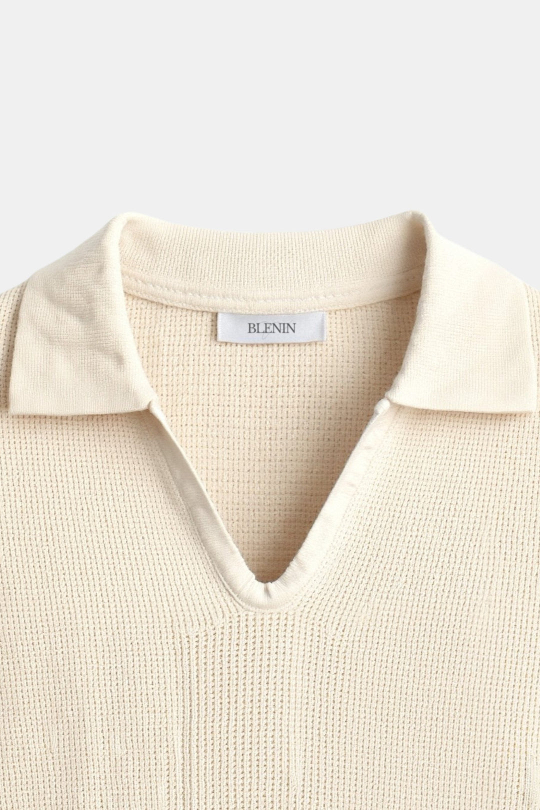 Felix Polo à manches courtes pour homme, col V avec col classique, tricot beige avec fines rayures noires, style tendance et moderne, vue rapprochée sur le col et la partie supérieure du polo.