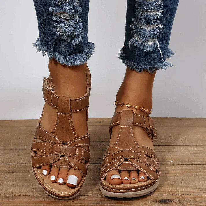 Sandales plates femme marron avec brides tressées et fermeture à scratch à la cheville, semelle confortable, style moderne pour l’été.