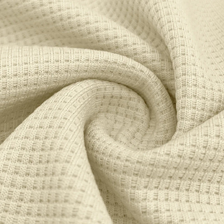 Zoom sur le tissu du polo homme Firmin, en maillage texturé de couleur crème. Ce tissu doux et respirant offre un confort optimal tout en apportant un style raffiné et moderne à votre tenue.