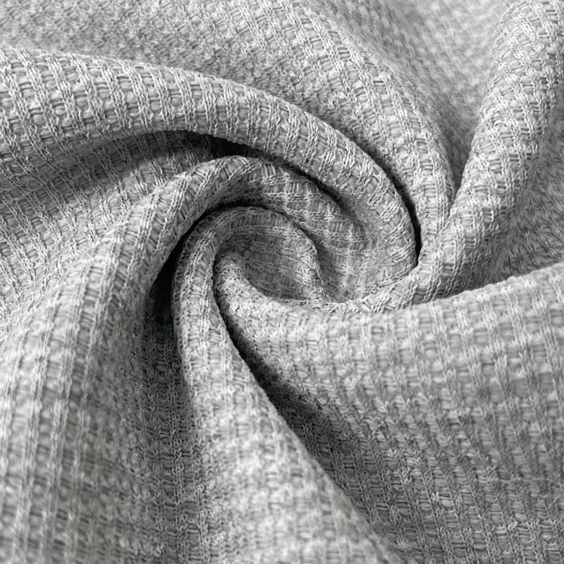 Zoom sur le tissu du polo homme Firmin, en maillage texturé de couleur grise. Ce tissu léger et respirant assure un confort optimal tout en apportant un look élégant et moderne à votre tenue.