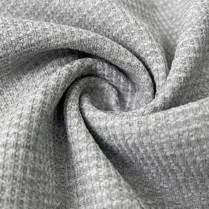 Zoom sur le tissu du polo homme Firmin, en maillage texturé de couleur grise. Ce tissu léger et respirant assure un confort optimal tout en apportant un look élégant et moderne à votre tenue.