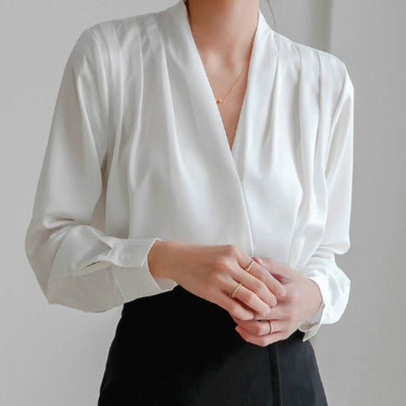 Blouse élégante blanche en tissu fluide, col en V croisé, manches longues, coupe raffinée idéale pour un look professionnel ou habillé.
