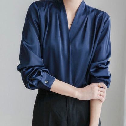  Blouse élégante en satin bleu marine, manches longues avec poignets boutonnés, col en V croisé, idéale pour un look professionnel et raffiné.