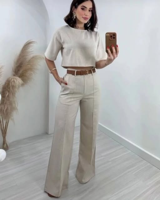 cet ensemble beige chic comprend un top court à manches courtes et un pantalon évasé à taille haute, accompagné d'une ceinture en cuir. Une silhouette moderne et élégante, parfaite pour un look à la fois décontracté et sophistiqué.