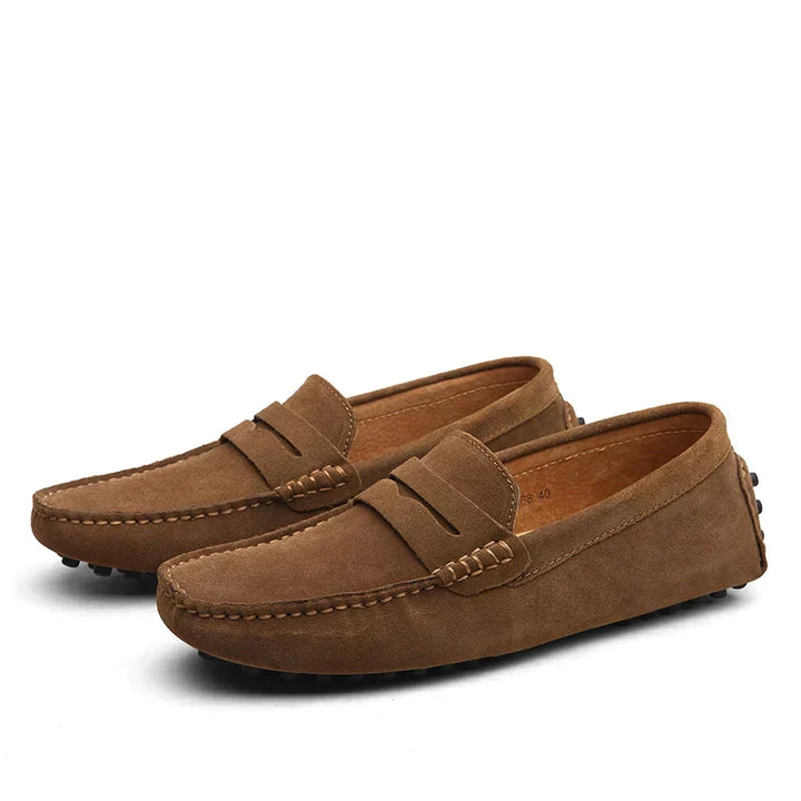 Une paire de mocassins en daim marron, au design raffiné et moderne. Confortables et stylés, ces mocassins sont idéaux pour un look élégant et décontracté, parfaits pour toutes les occasions.