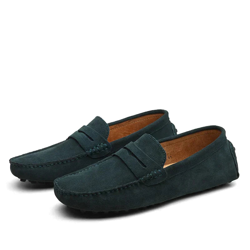 Une paire de mocassins en daim vert foncé, au design élégant et moderne. Parfaits pour un look sophistiqué et décontracté, ces mocassins offrent à la fois confort et style, idéals pour toutes les occasions.
