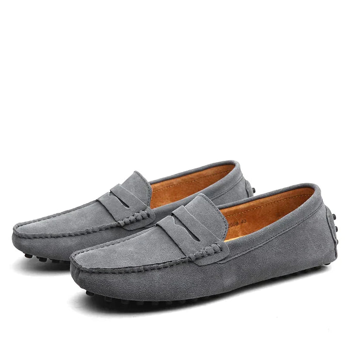Une paire de mocassins en daim gris, élégants et confortables, avec un design classique et une finition soignée. Parfaits pour un look décontracté et stylé, ces mocassins apportent une touche moderne à vos tenues.
