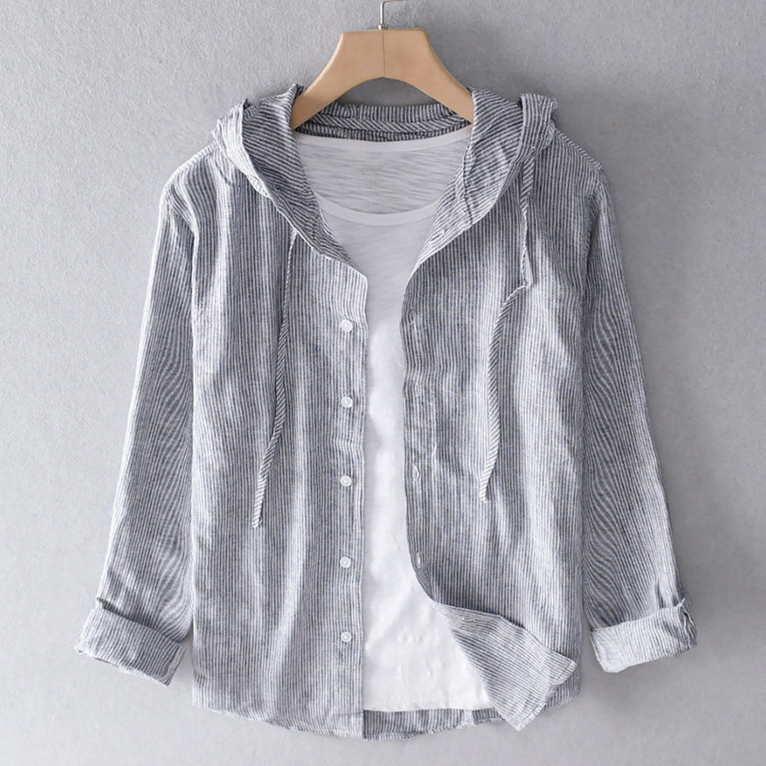 Blouse à capuche gris à fines rayures, boutonnée, manches longues retroussées, présentée sur cintre avec un t-shirt blanc en dessous.