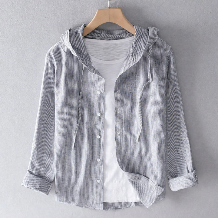 Blouse à capuche gris à fines rayures, boutonnée, manches longues retroussées, présentée sur cintre avec un t-shirt blanc en dessous.