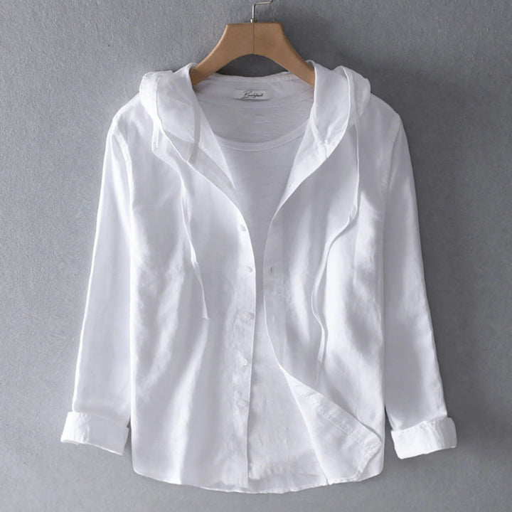 Blouse à capuche blanche unie, boutonnée, manches longues retroussées, présentée sur cintre avec un t-shirt blanc en dessous.