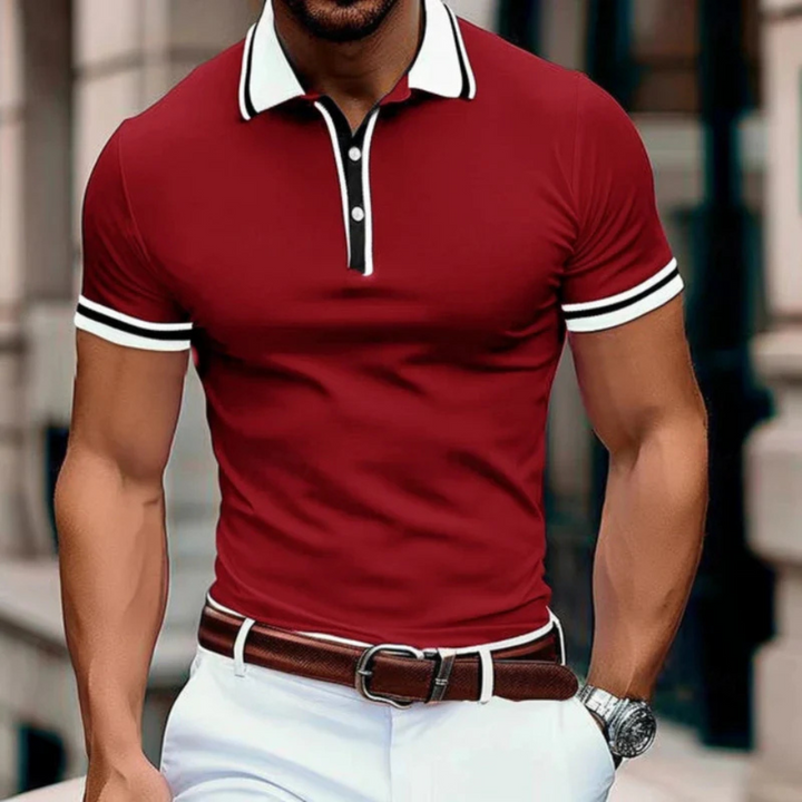 Homme portant le polo d’été Gaston rouge ajusté, avec col blanc contrasté et liserés blancs aux manches, associé à un pantalon blanc, une ceinture marron et une montre.