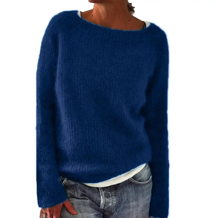 Femme portant un pull bleu en maille à la coupe décontractée, à manches longues et à large encolure, associé à un t-shirt clair et un jean, photographiée sur fond blanc.