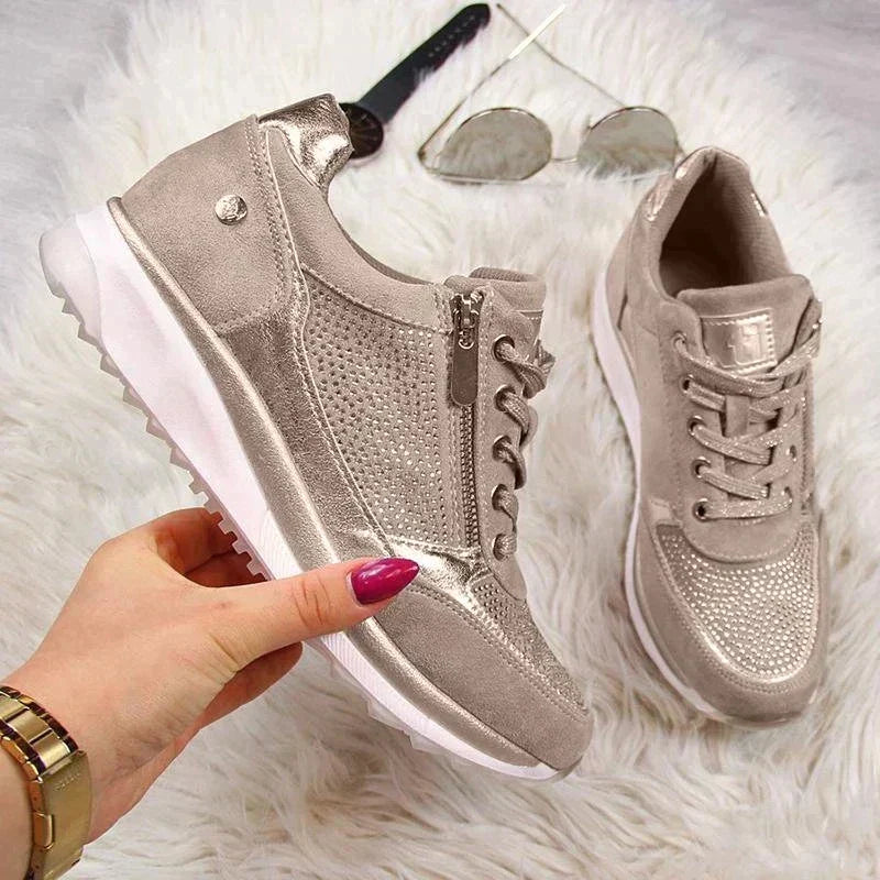 Chaussures pour femme métalliques argentées, avec des détails en strass et une fermeture éclair pratique sur le côté. Elles sont accompagnées de lacets et d’une semelle confortable, offrant à la fois style et confort. Accessoirisées avec des lunettes de soleil et une montre, idéales pour une tenue moderne et élégante.