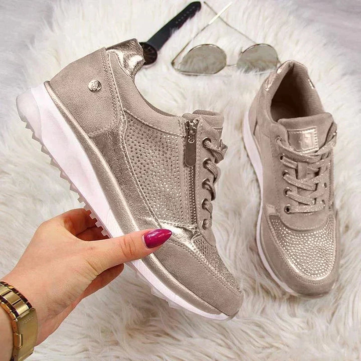 Chaussures pour femme métalliques argentées, avec des détails en strass et une fermeture éclair pratique sur le côté. Elles sont accompagnées de lacets et d’une semelle confortable, offrant à la fois style et confort. Accessoirisées avec des lunettes de soleil et une montre, idéales pour une tenue moderne et élégante.