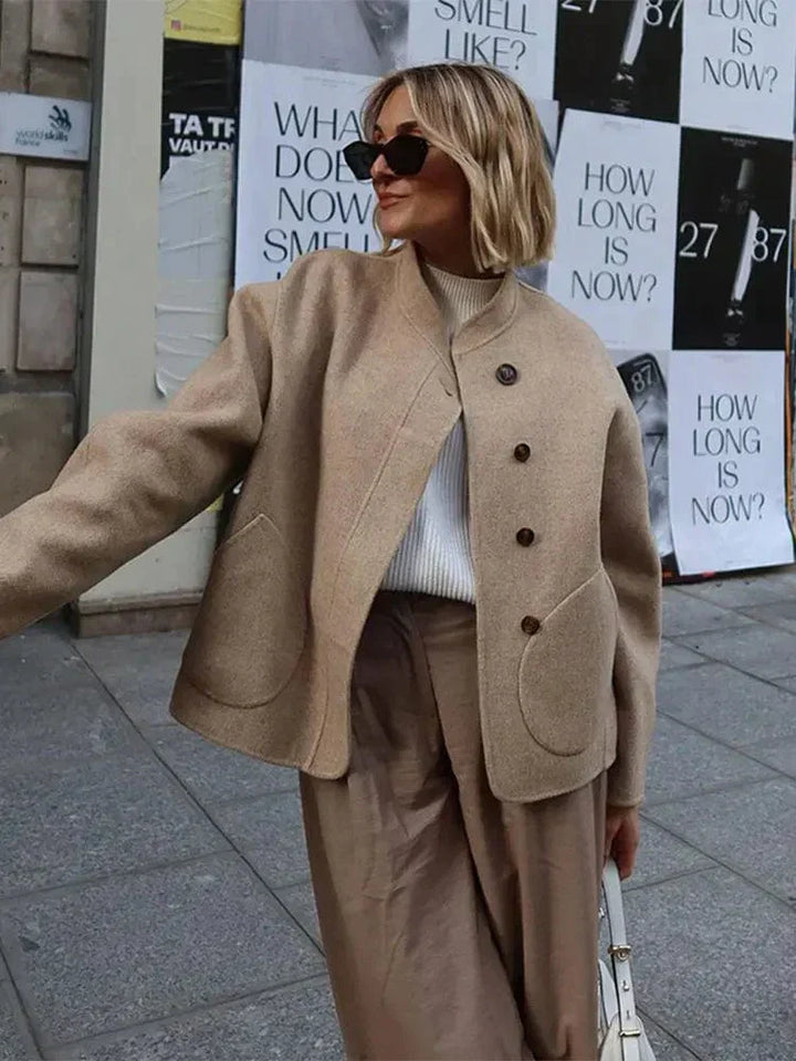 Veste courte pour femme en laine douce et élégante, idéale pour la saison hivernale. Ses boutons en bois et ses poches arrondies ajoutent une touche chic et moderne. Parfaite pour une tenue décontractée ou élégante, elle se porte facilement avec un pull ou une blouse, offrant confort et chaleur lors des journées fraîches.