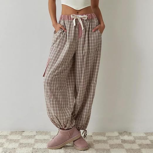 Pantalon de pyjama pour femme porté de face, à coupe ample, en tissu à carreaux beige et rose, avec taille élastique et lien à nouer, poches latérales et bas resserrés, pour un confort optimal et un style tendance à la maison.