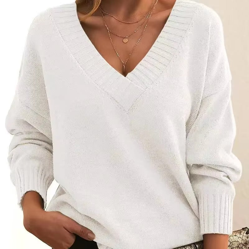 Femme portant un pull en maille blanc à col en V avec bords côtelés. Les manches longues sont légèrement amples, et elle porte plusieurs colliers fins en or. Ce look moderne et élégant combine simplicité et féminité, tout en étant confortable et intemporel.
