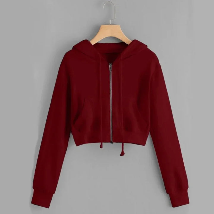 Un sweat à capuche rouge bordeaux avec une fermeture éclair à l'avant. Ce modèle court possède des manches longues et une coupe ajustée, parfait pour un look décontracté et stylé.