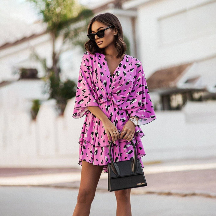 Robe courte rose avec imprimé floral noir, design à volants et manches amples, parfaite pour un look estival tendance et féminin.