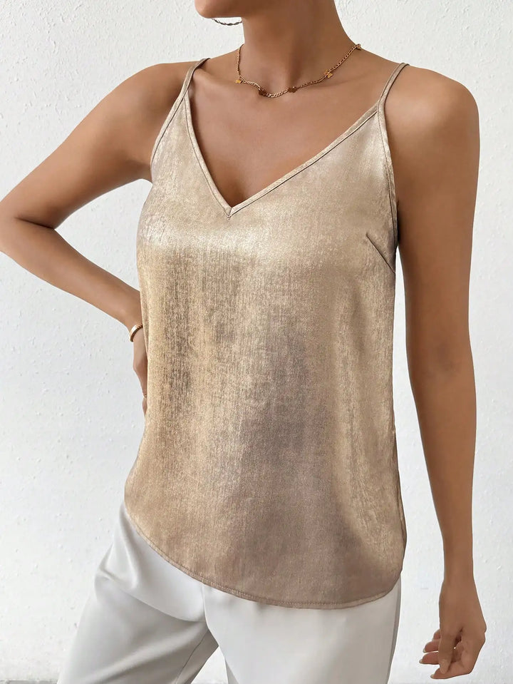 Débardeur élégant à fines bretelles et col en V, dans une teinte dorée brillante. Ce modèle moderne, porté avec un pantalon blanc, est parfait pour un look chic et raffiné, idéal pour les journées ensoleillées ou une soirée décontractée.