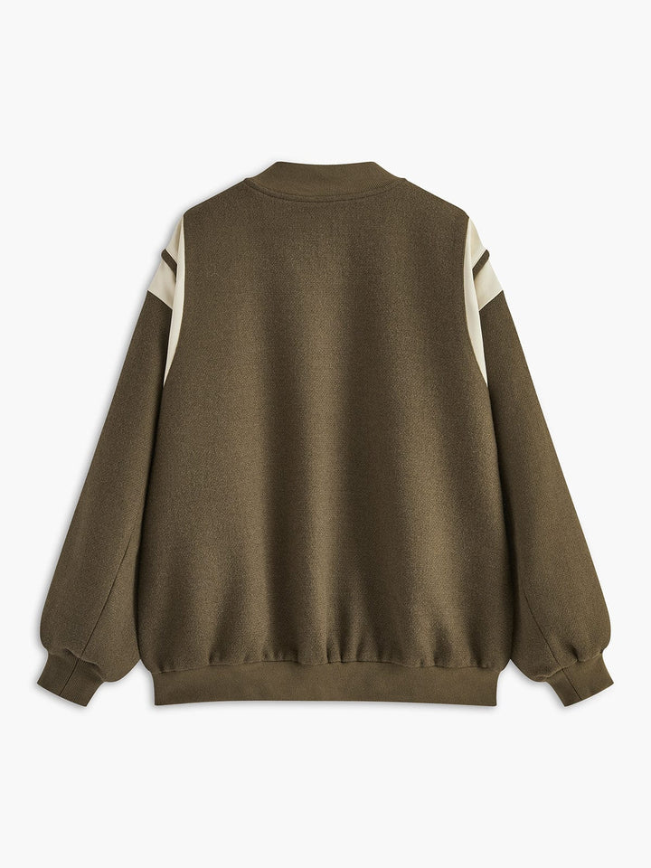 veste varsity kaki olive avec empiècements crème sur les épaules et les manches, fermeture par boutons-pression argentés, poches plaquées, coupe légèrement oversize et bord-côtes, look tendance en extérieur.