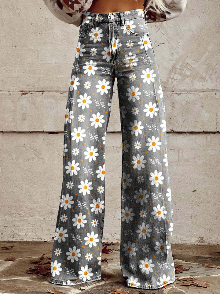 Une femme portant un pantalon à taille haute et coupe large avec un fond gris et un imprimé floral joyeux featuring des marguerites blanches et des centres jaunes. Le pantalon est conçu pour un look décontracté et sportif, parfait pour une tenue chic et confortable.