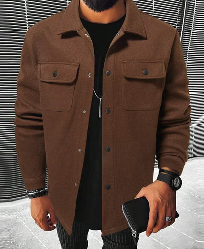 Jules | Chemise oversize pour homme à manches longues, couleur marron, avec poches à rabat et boutons noirs, portée sur un t-shirt noir avec un pantalon à rayures.