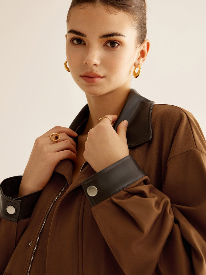 Détail de la veste oversize Kylora pour femme, mettant en valeur le col en cuir noir et les boutons métalliques. Le modèle porte la veste ouverte, avec une attention particulière sur les finitions élégantes, ajoutant une touche moderne et tendance à l'ensemble.