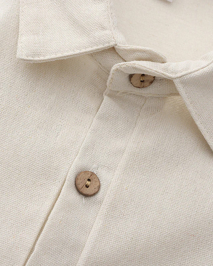 Zoom sur le col et les boutons en bois du polo en lin pour homme, couleur beige clair. Le design épuré et les détails soignés ajoutent une touche de raffinement à ce modèle léger et estival.
