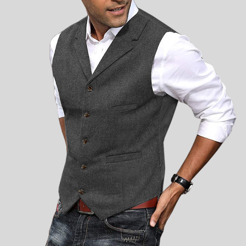Gilet court sans manches gris à boutons, coupe ajustée avec poches, porté sur une chemise blanche avec jean.